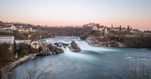 Scenic view of river by city against clear sky