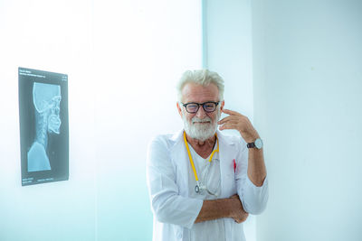 Caucasian male doctor is showing human brain skeleton x-ray film on the wall board in the hospital.