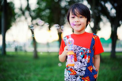 Portrait of smiling boy with toy on field