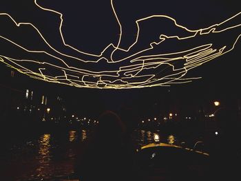 Rear view of woman against illuminated city at night