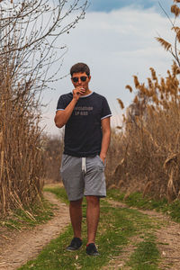 Full length of young man smoking cigarette while standing by plants