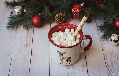 Cup of hot chocolate on white wooden background with christmas decor.