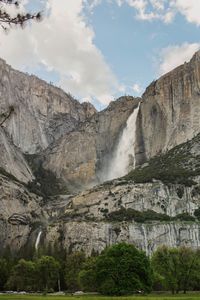 Low angle view of waterfall against cloudy sky
