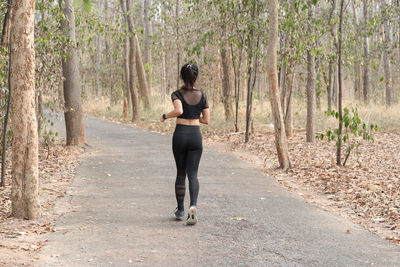 Full length rear view of man walking on road in forest