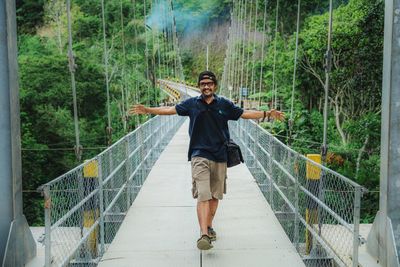 Man standing on footbridge in forest