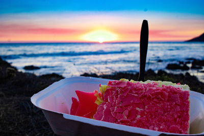 Close-up of chocolate on beach against sky during sunset