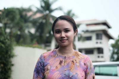 Portrait of beautiful woman against building in city