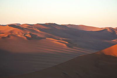 Scenic view of desert against clear sky during sunset