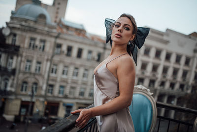 Portrait of woman standing against building in city