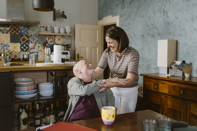 Happy woman greeting senior father-in-law sitting at home