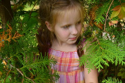 Girl looking away while standing amidst plants