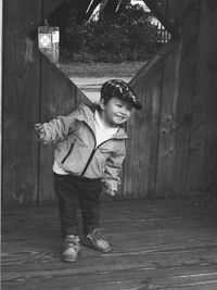 Smiling boy standing against wooden structure