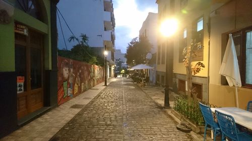 Empty alley amidst buildings in city at night