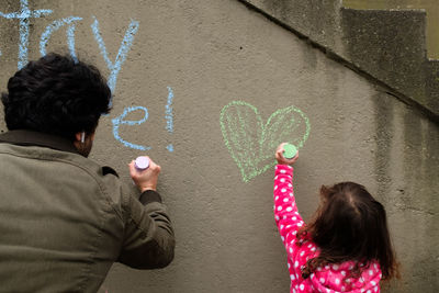 Father and daughter draw encouraging messages with chalk