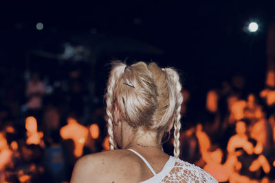 Rear view of woman with arms outstretched at night