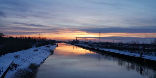 Scenic view of frozen canal against sky during sunset