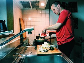 Side view of man standing in kitchen