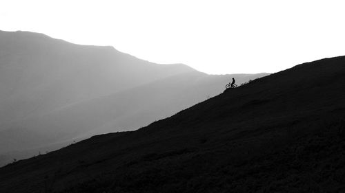 Scenic view of silhouette mtb rider and mountain against sky