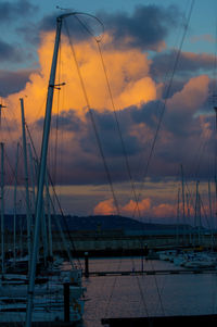 Sailboats moored in sea against sky at sunset