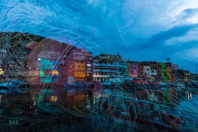 Digital composite image of fishing net and multi colored buildings at port against sky