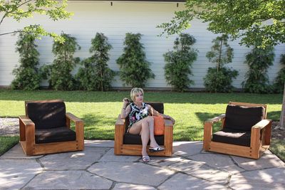 Portrait of woman sitting on chair against plants