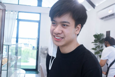 Portrait of smiling young man against window