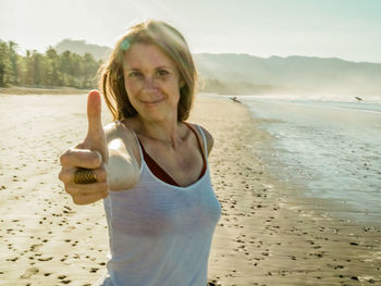 Portrait of smiling woman gesturing on beach