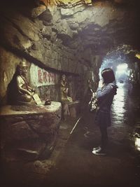 Full length of woman praying to buddha statue in cave