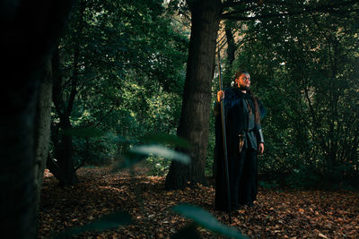 Serious jarl supreme ruler of vikings wearing national outfit and eyepatch standing in forest at historical reenactment