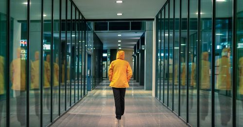 Rear view of man walking in illuminated building