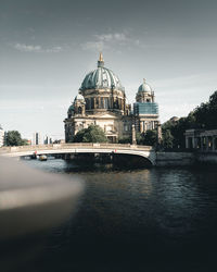 View of church by river against sky in city