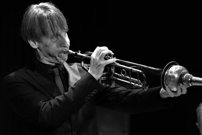 Man playing trumpet against black background