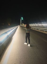 Rear view of man standing on road at night