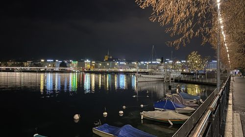 Illuminated harbor by river against sky at night