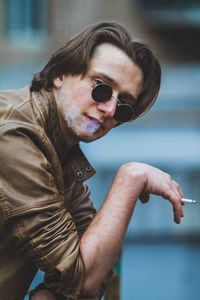 Close-up portrait of man wearing sunglasses smoking cigar