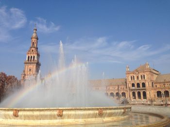 Rainbow over fountain at plaza de espana against sky