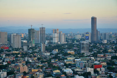 Aerial view of modern buildings in city against sky during sunset