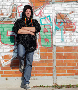 Fashionable mature man standing against graffiti wall