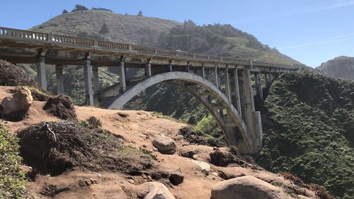 Arch bridge over rocks against sky