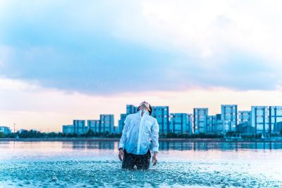 Rear view of man looking at cityscape against sky