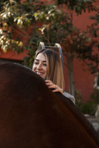 Young blonde woman with her brown horse enjoys a day on the farm.