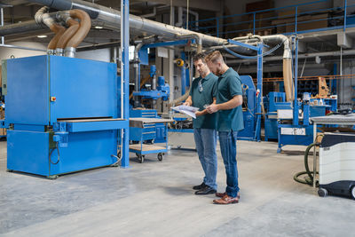 Two carpenters standing and talking in production hall