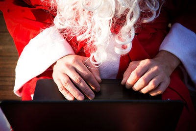Midsection of man wearing santa claus costume using laptop