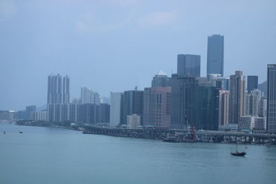 Sea by modern buildings against sky in city