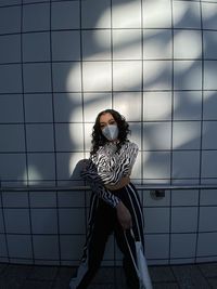 Young woman sitting on floor against wall