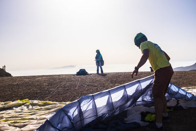 People on shore against clear sky