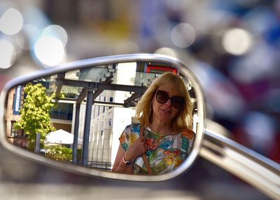 Mature woman reflecting on side-view mirror of motorcycle