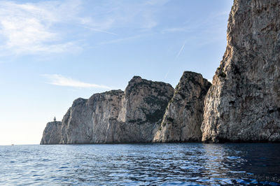 Rock formations by sea against sky