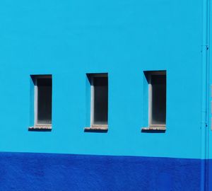 Blue wall with 3 windows of building