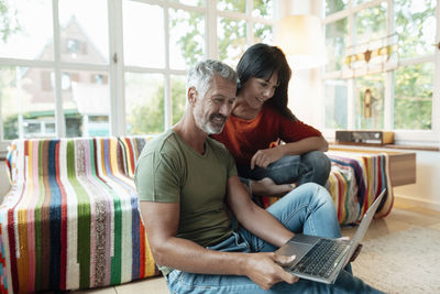 Smiling mature couple using laptop at home